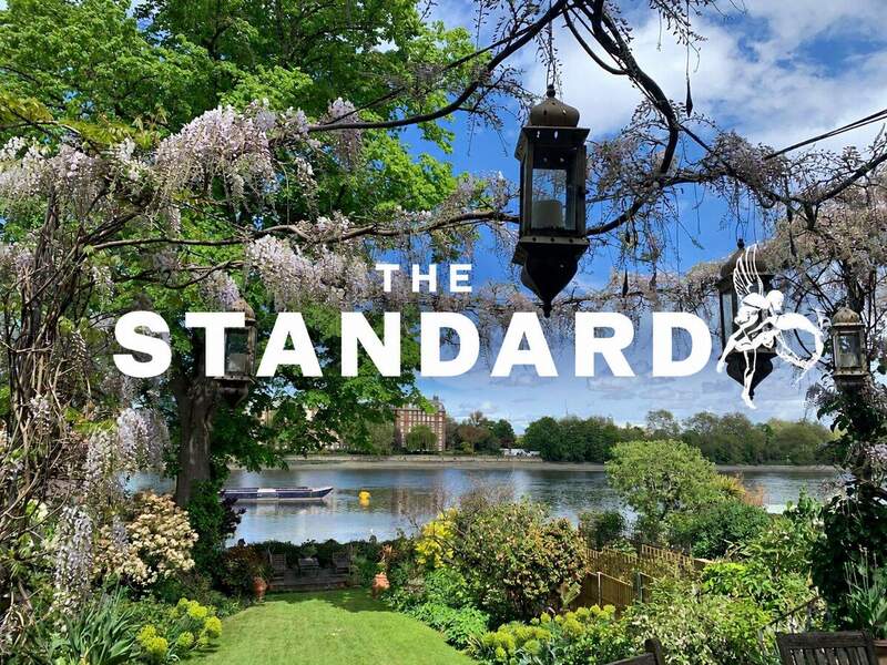 Riverside garden overlooking the Thames in Putney, with The Standard logo in white.